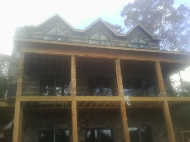 Dormers and porch framing on a large log home under construction — Roof Coating work by our crew in Sedley