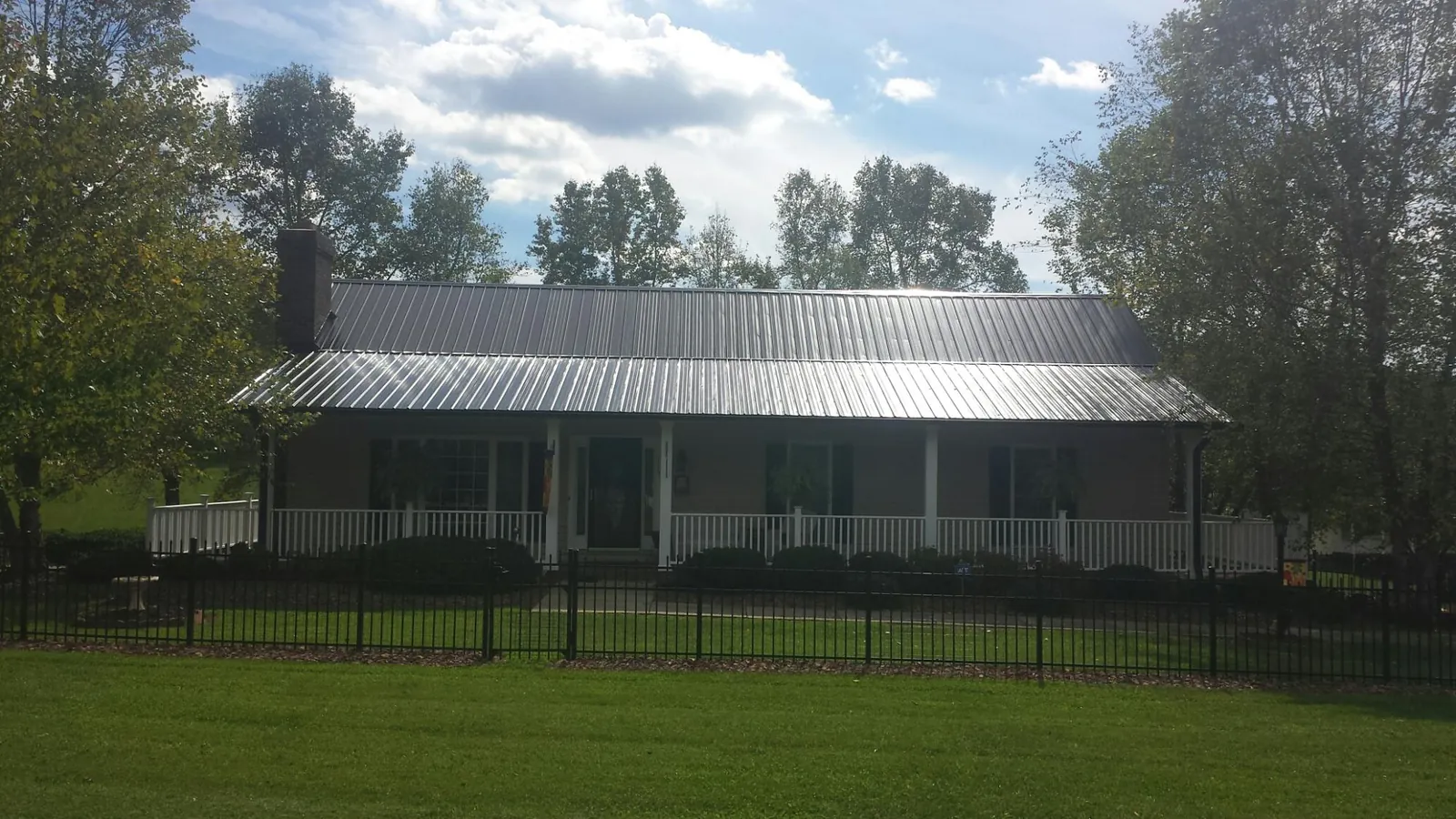 Gray metal roof on a brick ranch with a full width front porch — Gutter Guard Installation work by our crew in Sedley