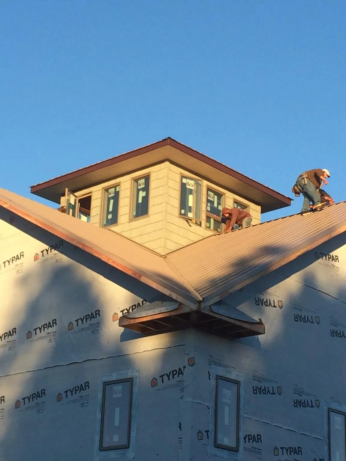 Roofers working around a rooftop cupola on a new metal roof at sunset — Roof Waterproofing in Sedley by Roofing Brothers